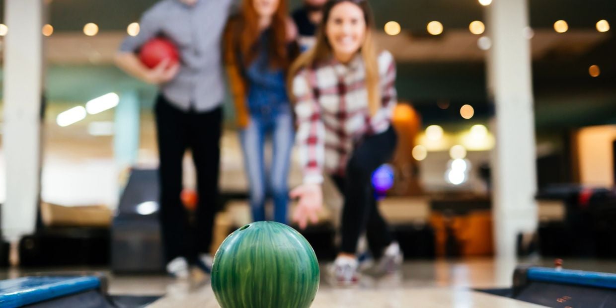 Happy friends having fun and enjoying playing bowling together